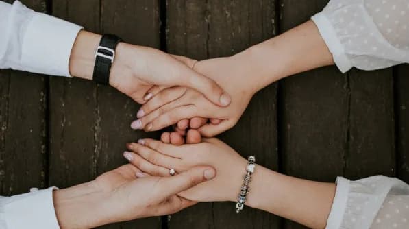 Two pairs of hands clasped together in mutual support